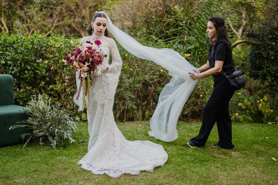 Assessora da Rito Eventos ajustando o véu da noiva no jardim antes da cerimônia
