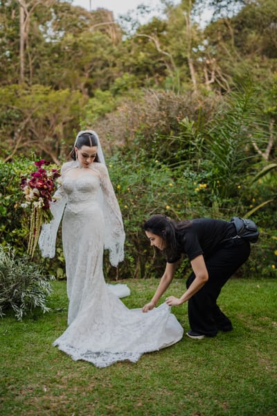 Assessora da Rito Eventos ajeitando a cauda do vestido da noiva no jardim