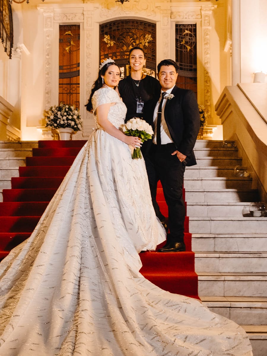 Noivos e a assessora da Rito Eventos na escadaria do local da festa de casamento