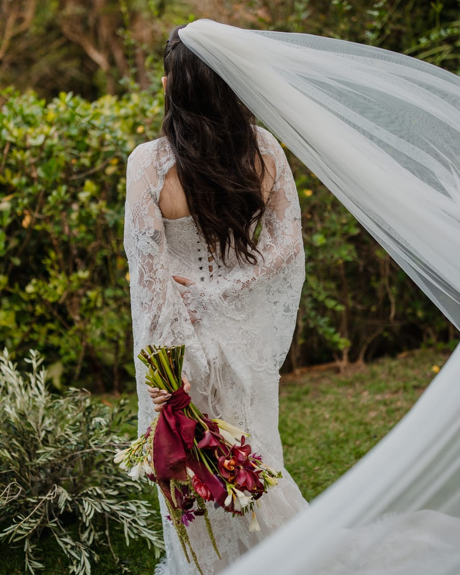 Noiva com véu ao vento segurando buquê em casamento assessorado pela Rito Eventos